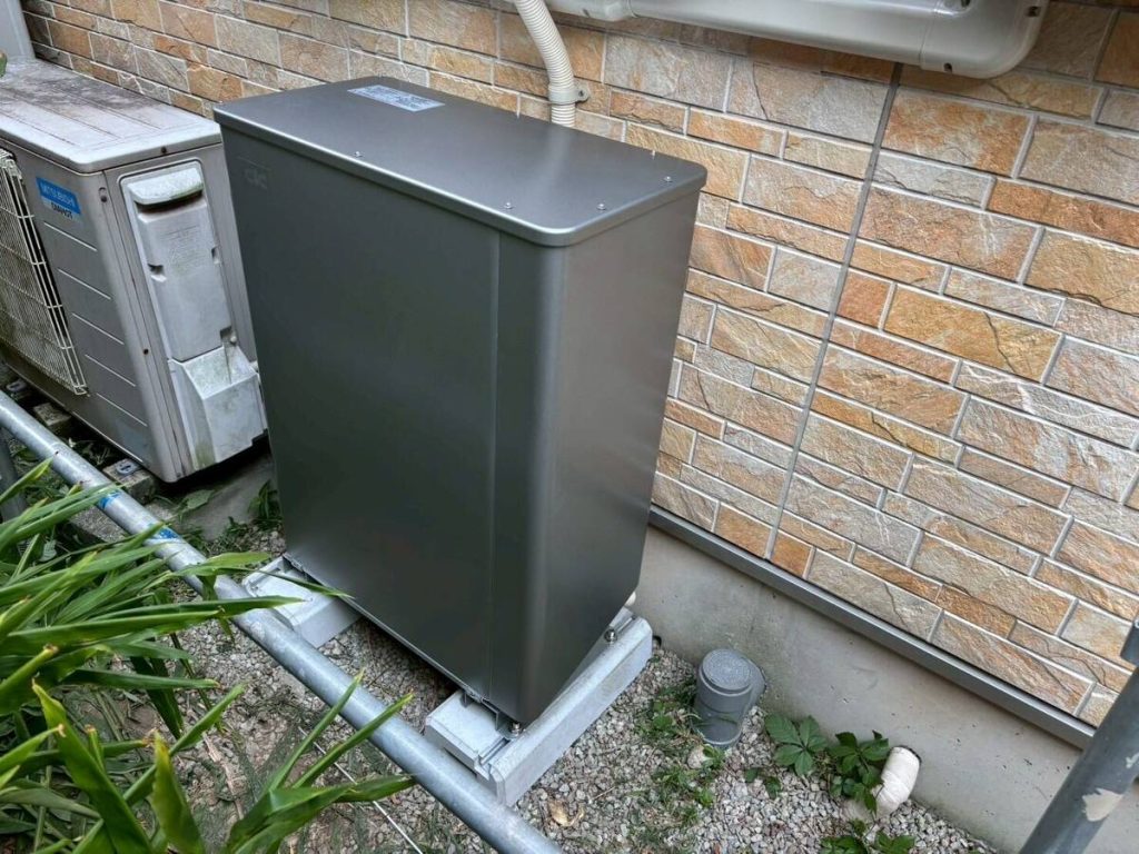 濃色の蓄電池と外壁に並ぶ三台の関連機器