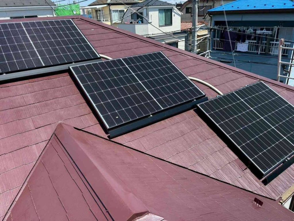 赤い金属屋根の太陽光パネルと白色蓄電池
