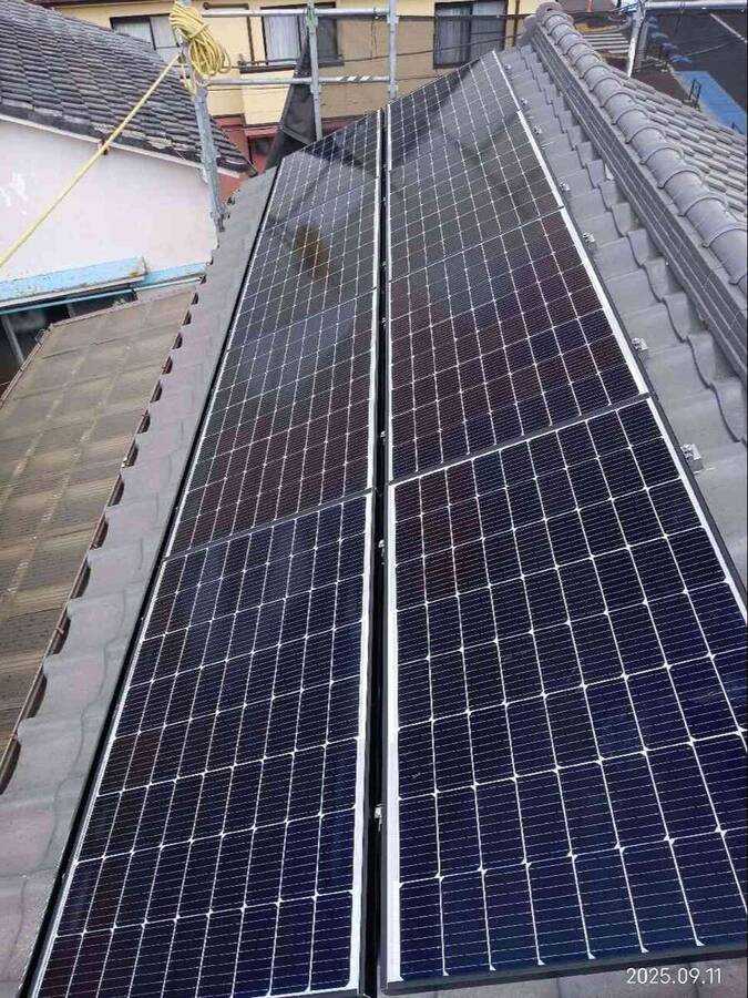 細長い瓦屋根の太陽光パネルと白色蓄電池